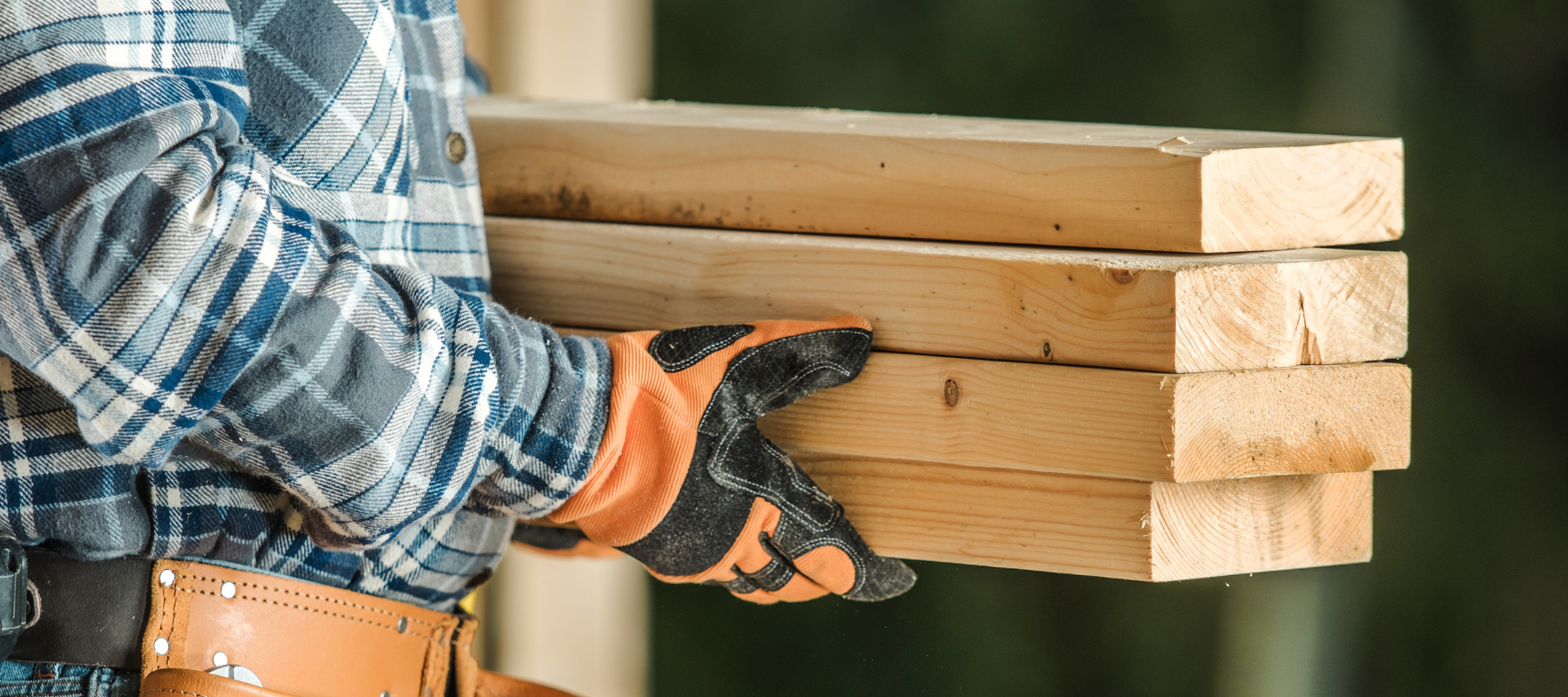 A stack of lumber boards being carried by hand